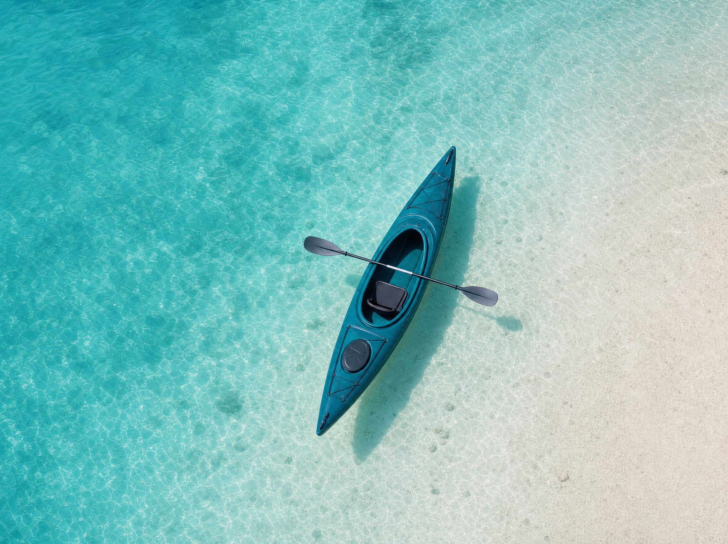 A kayak on clear teal water seen from above